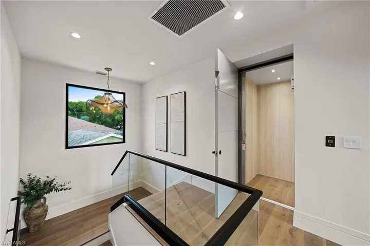 Stairway with wood finished floors and recessed lighting