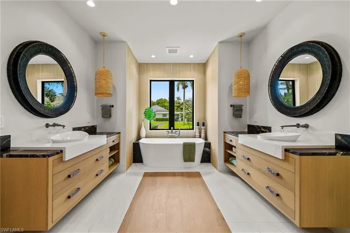 Bathroom with two vanities, a soaking tub, wood finished floors, and recessed lighting