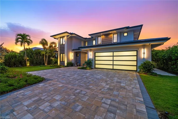 View of front of home featuring decorative driveway, stucco siding, and a front yard