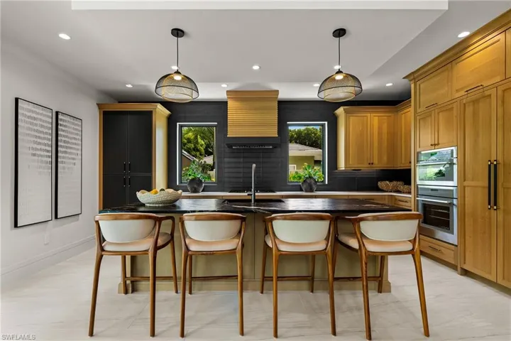 Kitchen with recessed lighting, double oven, dark countertops, a breakfast bar, and decorative light fixtures