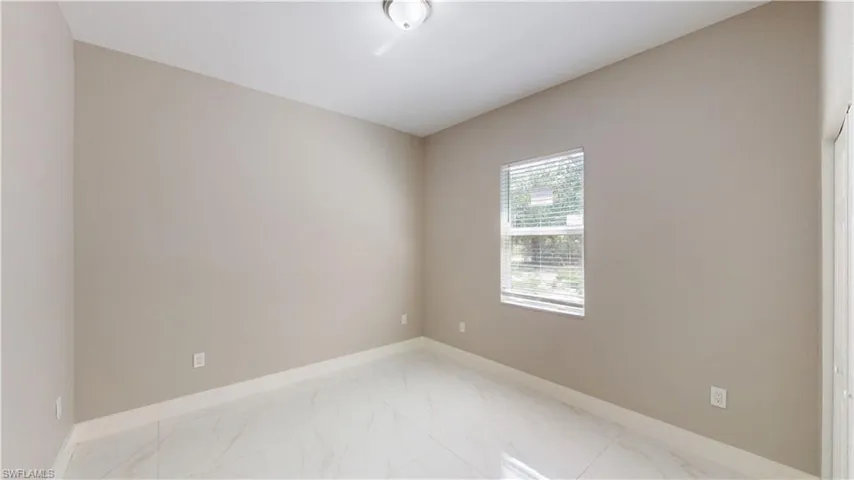 Spare room with light marble finish flooring and baseboards