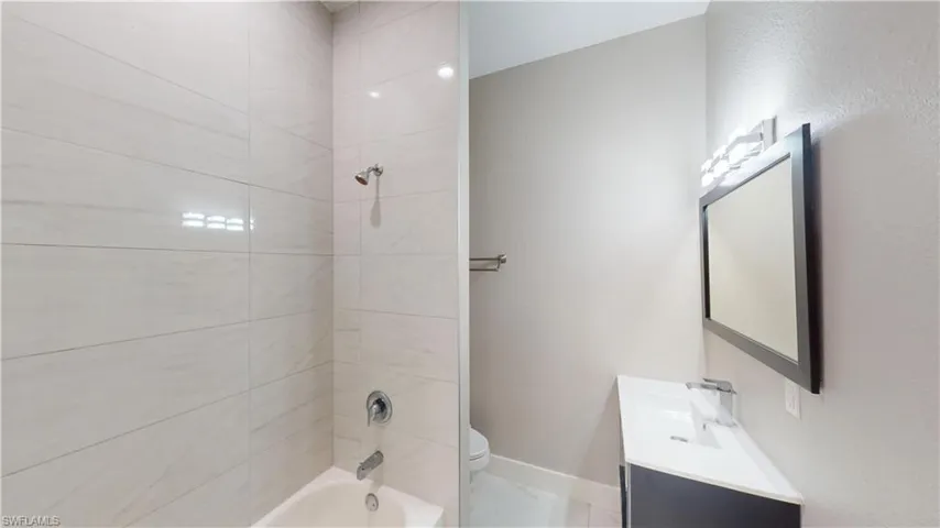 Full bathroom with toilet,  shower combination, baseboards, and vanity