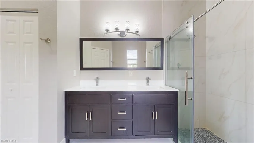 Bathroom featuring a marble finish shower and double vanity