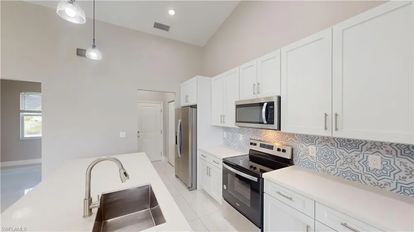 Kitchen featuring stainless steel appliances, a sink, high vaulted ceiling, tasteful backsplash, and light countertops