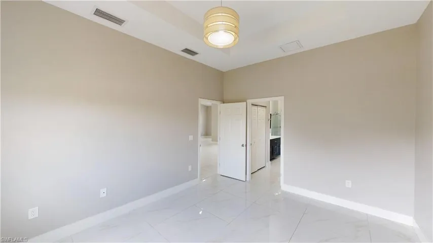 Spare room featuring light marble finish flooring and baseboards
