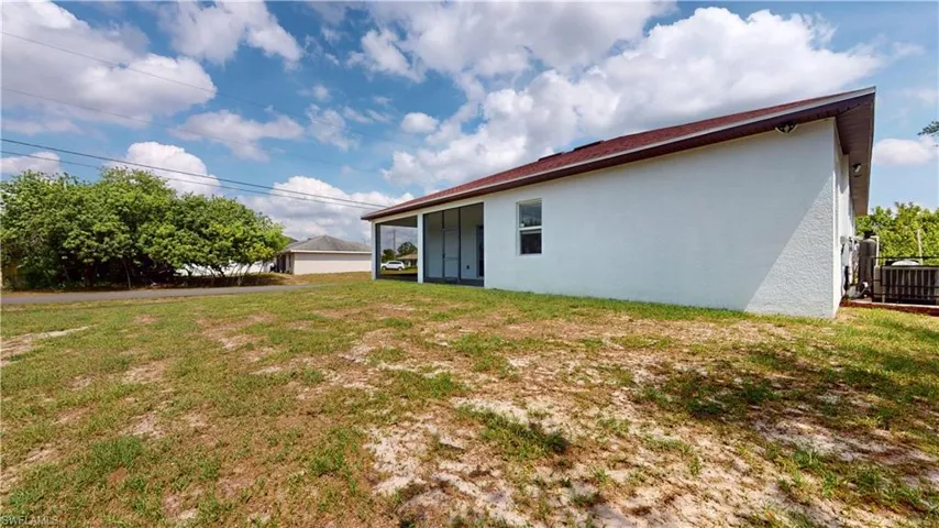 Back of house with stucco siding, a lawn, and central AC