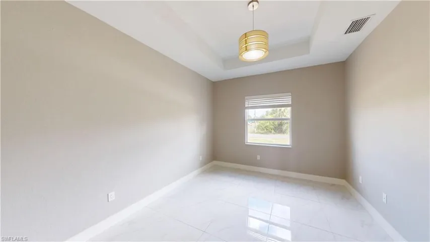 Unfurnished room featuring light marble finish flooring, baseboards, and a raised ceiling