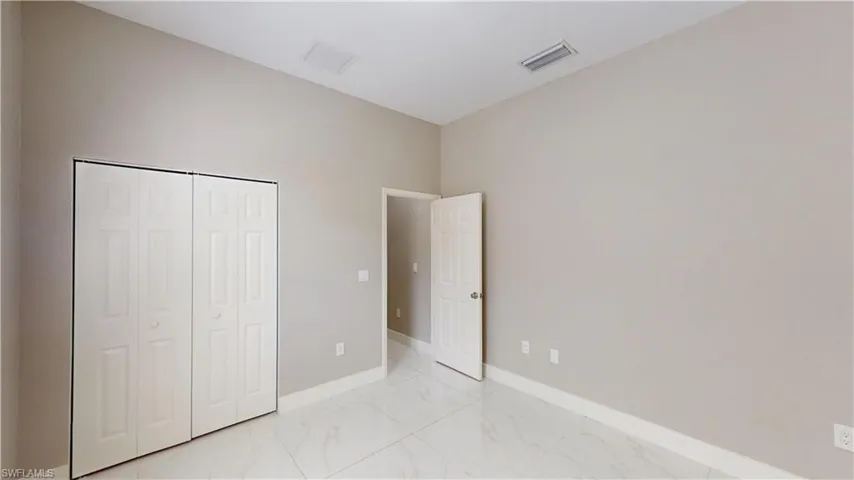 Unfurnished bedroom with light marble finish flooring, a closet, and baseboards