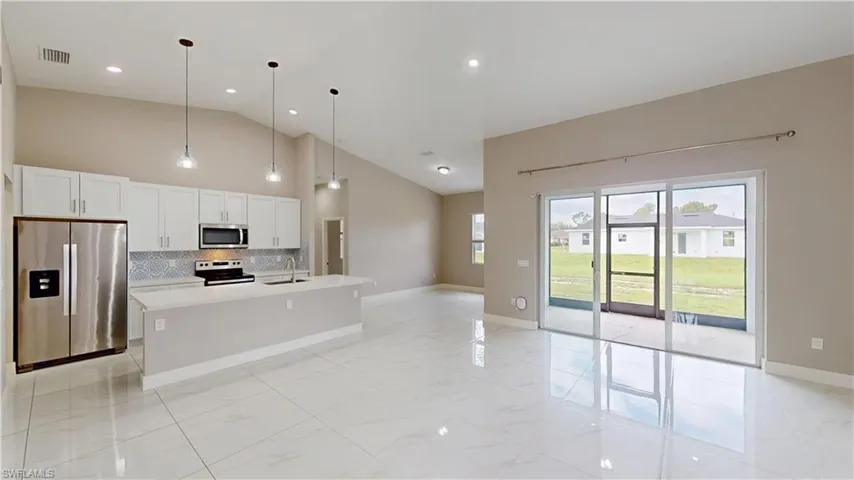 Kitchen with stainless steel appliances, a sink, tasteful backsplash, light countertops, and high vaulted ceiling