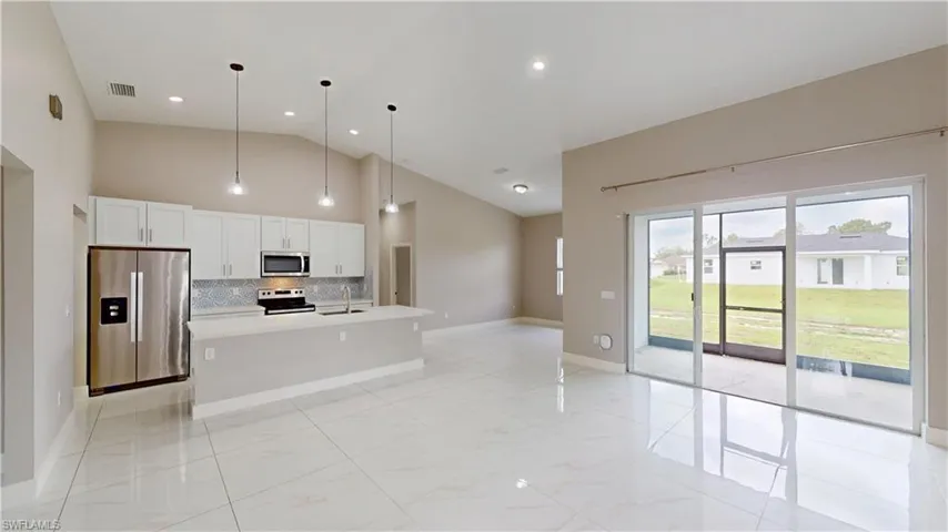 Kitchen featuring appliances with stainless steel finishes, a sink, high vaulted ceiling, backsplash, and light countertops