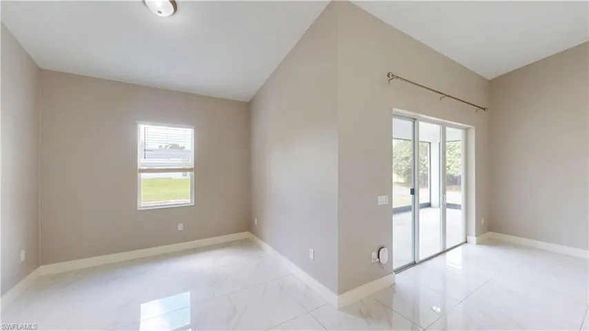 Spare room with healthy amount of natural light, marble look tile flooring, and baseboards