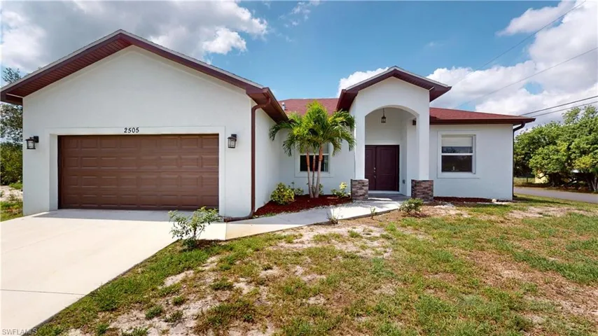 View of front of property with stucco siding, an attached garage, and driveway