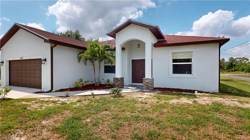 View of front of property with stucco siding, an attached garage, a front yard, and driveway