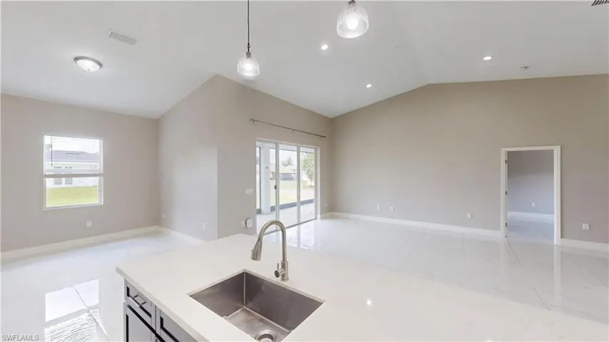 Kitchen with open floor plan, a sink, lofted ceiling, light countertops, and pendant lighting