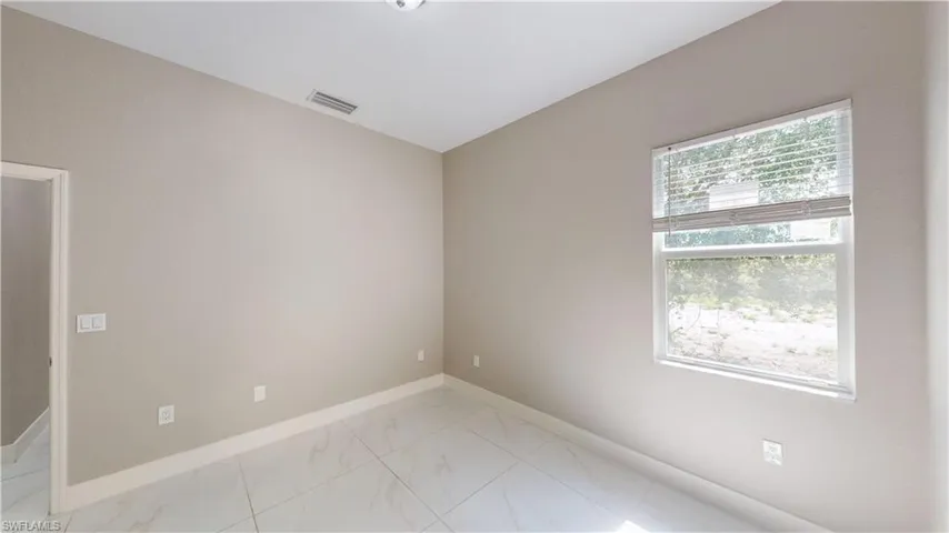 Unfurnished room featuring light marble finish floors and baseboards