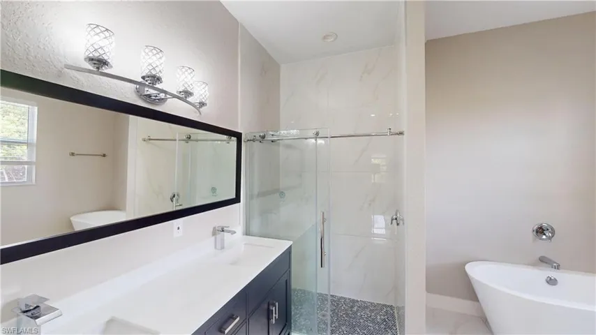 Full bath featuring a stall shower, a freestanding bath, and double vanity