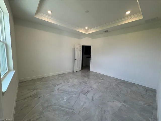 Unfurnished room with crown molding, marble finish floors, a raised ceiling, recessed lighting, and baseboards