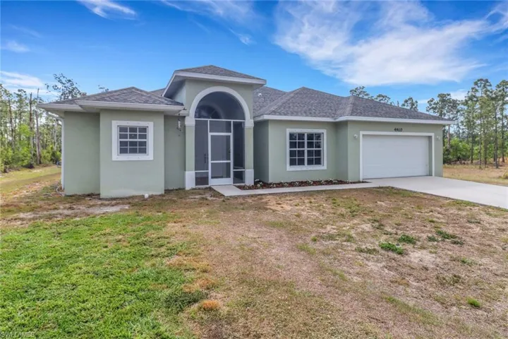 View of front of home with stucco siding, concrete driveway, roof with shingles, a front yard, and a garage