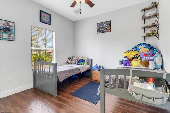 Bedroom featuring baseboards, wood finished floors, visible vents, and a ceiling fan