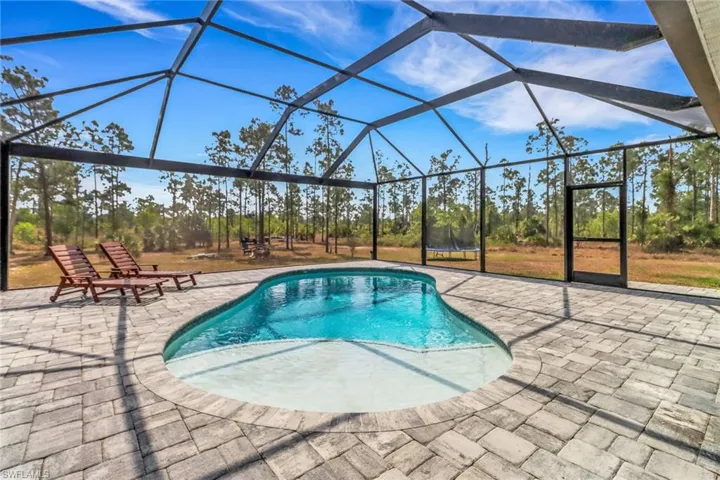 Outdoor pool featuring glass enclosure and a patio