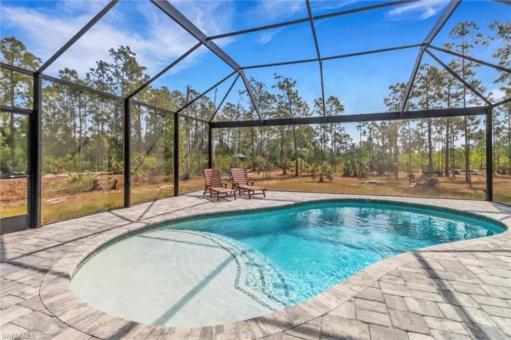 Outdoor pool featuring a patio area and glass enclosure