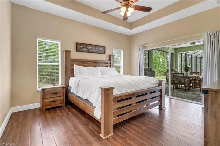 Bedroom featuring baseboards, multiple windows, access to exterior, and dark wood-style flooring