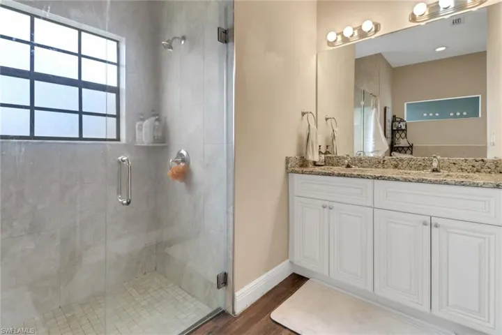 Full bath with a shower stall, wood finished floors, a sink, and double vanity