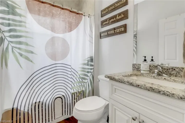 Full bath with vanity, curtained shower, and toilet