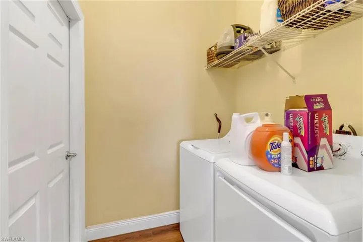 Laundry area featuring baseboards, separate washer and dryer, wood finished floors, and laundry area