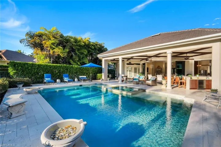 View of pool featuring a fenced backyard, a patio, a pool with connected hot tub, and an outdoor fire pit