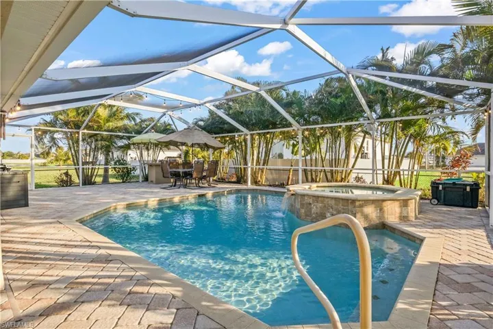 Sparkling in-ground pool with attached spa, surrounded by lush tropical landscaping—your own private oasis for year-round relaxation.