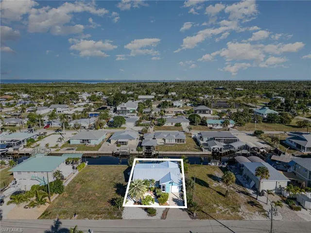 Aerial view of residential area with property parcel outlined and a nearby body of water