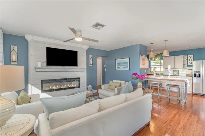 Living room with light wood-style floors, a ceiling fan, and a large fireplace
