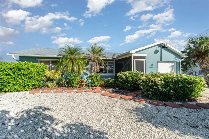Back of property with stucco siding, a garage, and a sunroom