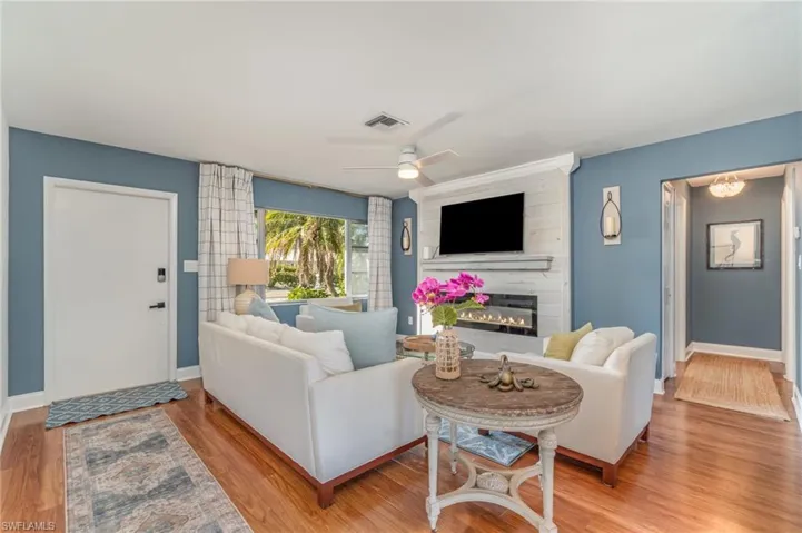 Living area featuring light wood-style flooring, a fireplace, and ceiling fan