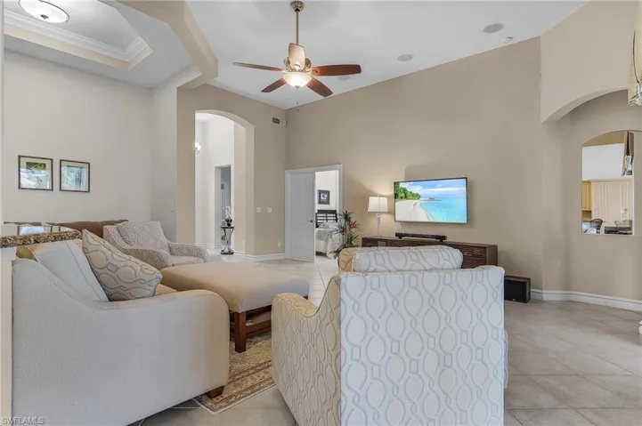 Tiled living room with ceiling fan and crown molding