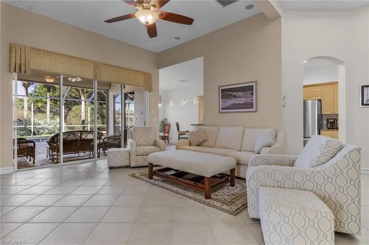 Living room with ceiling fan, beam ceiling, light tile patterned floors, and high vaulted ceiling