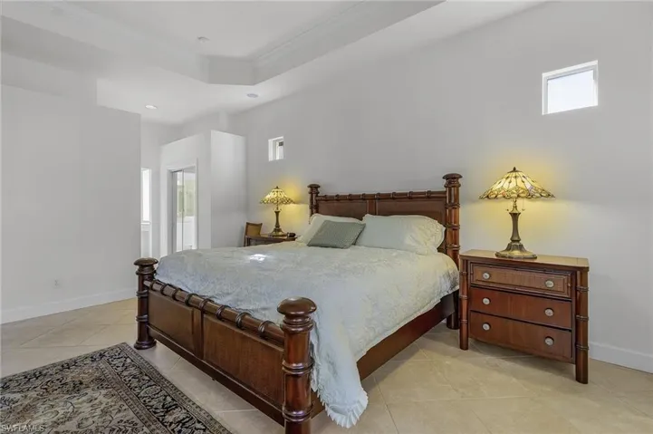 Bedroom with a tray ceiling, crown molding, and light tile patterned floors