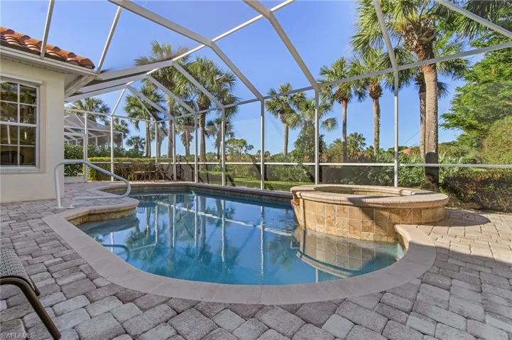 View of swimming pool featuring glass enclosure, an in ground hot tub, and a patio