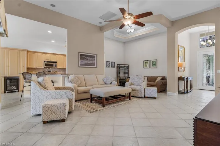 Tiled living room with a towering ceiling, ceiling fan with notable chandelier, and crown molding