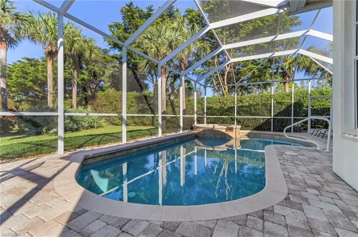 View of swimming pool with glass enclosure and a patio area