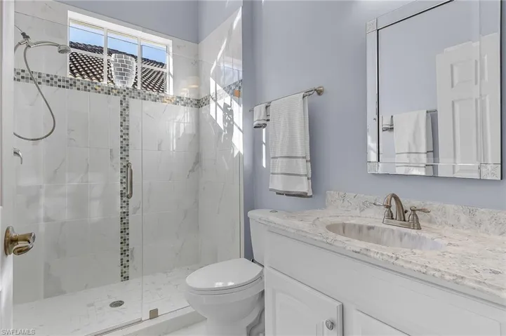Bathroom featuring vanity, a shower with shower door, and toilet