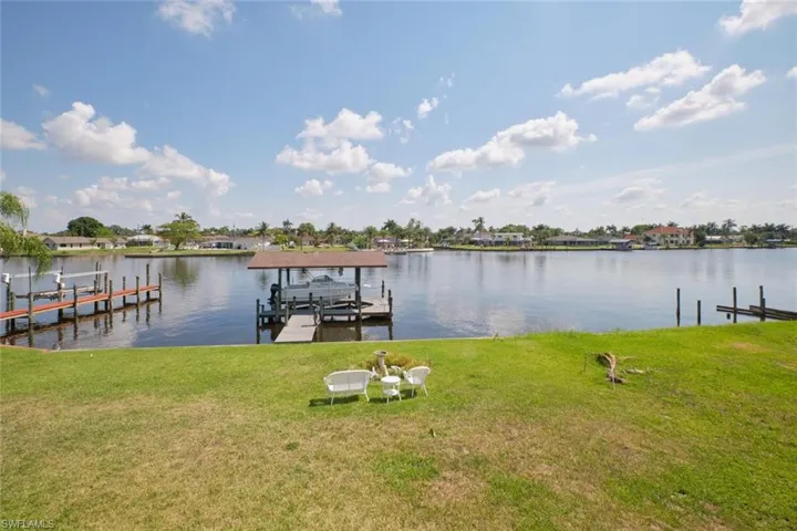 View of dock featuring a lawn and a water view