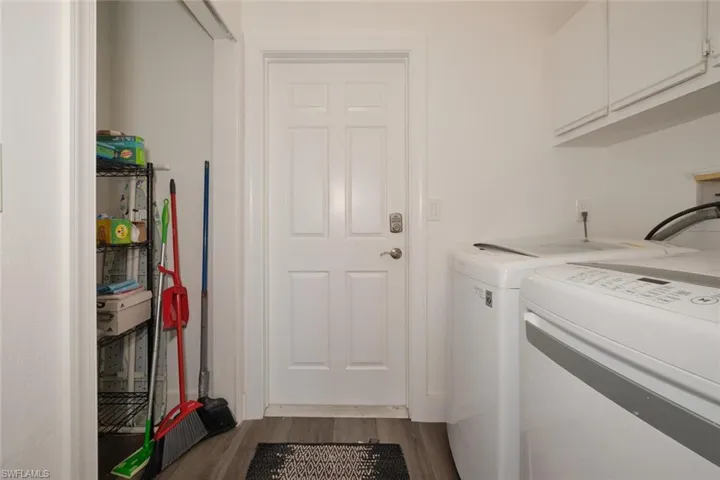 Laundry room with hardwood / wood-style floors, washing machine and dryer, and cabinets
