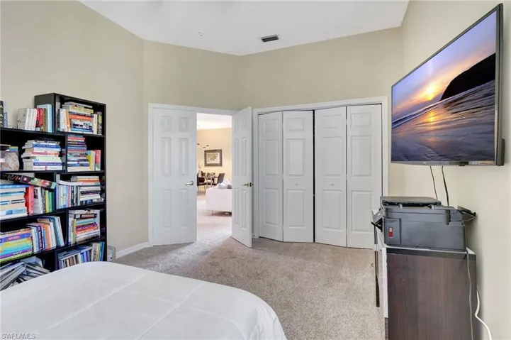 Carpeted bedroom with baseboards, visible vents, and a closet