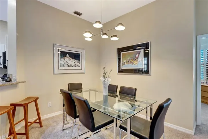 Carpeted dining space with an inviting chandelier, visible vents, and baseboards