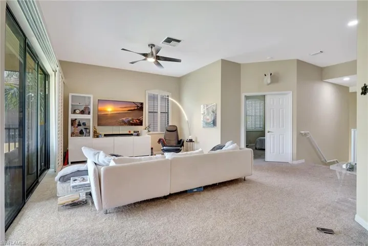 Carpeted living area featuring visible vents and ceiling fan