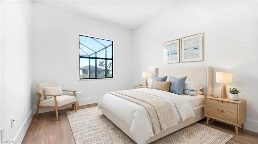 Spacious bedroom featuring wood-finish flooring, white walls, and a large window