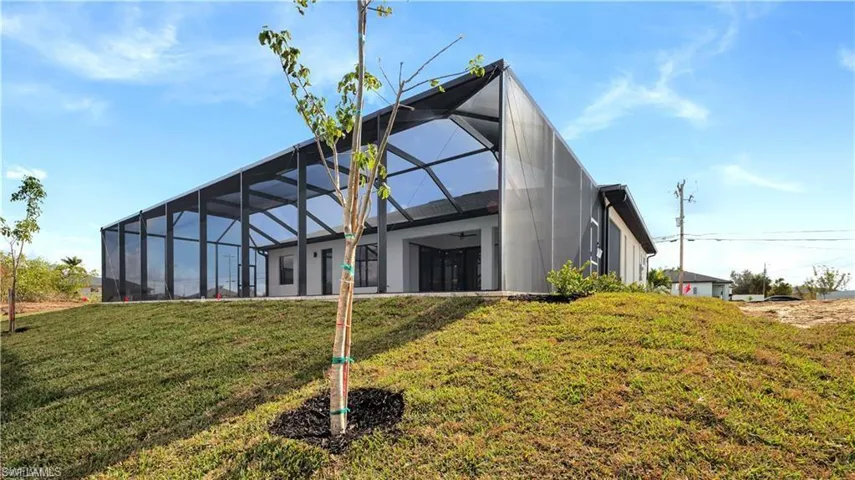 Rear view of house featuring a lawn and glass enclosure