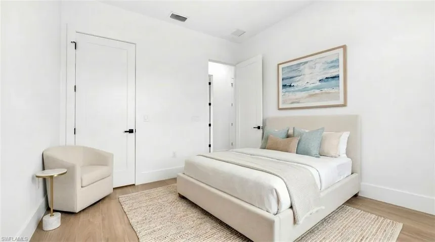 Bright interior space featuring wood-finish flooring, white walls, and a recessed air vent